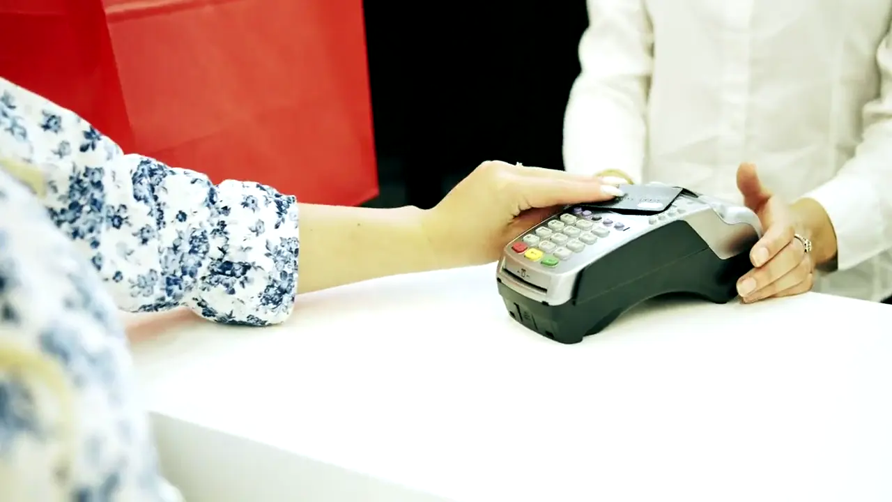 Customer paying by card on a point-of-sale terminal at a shop counter